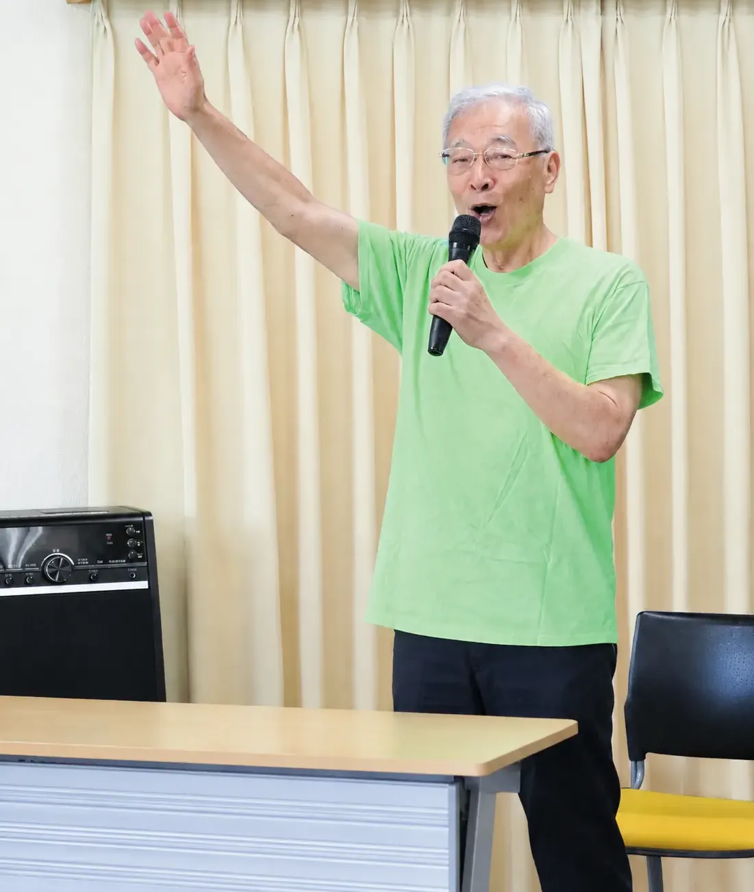 マイクを持ち、地域の活動で参加者に話しかける吉田医師